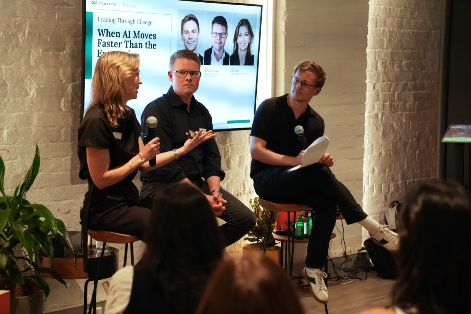 Three panellists seated on stage in front of an audience at the Sydney panel event.